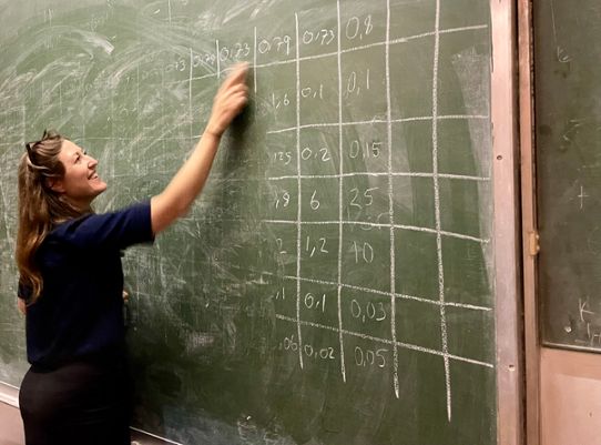 Sara Schützer writes on a  blackboard in a classroom in Zimbabwe.
