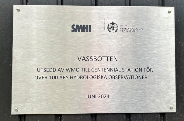 Graverad skylt frå WMO med texten VASSBOTTEN. Utsedd till centennieal station för över 100 års hydrologiska observationer. Juni 2024.