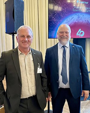 Två män framför en bildskärm där det står EUMETSAT 40 - Trusted in Space, Essential on Earth.