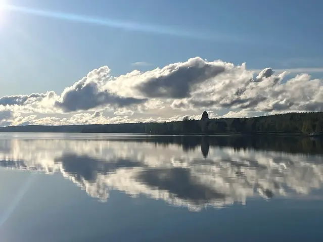 Sjövattenyta en solig vårdag, kyrka i fjärran.