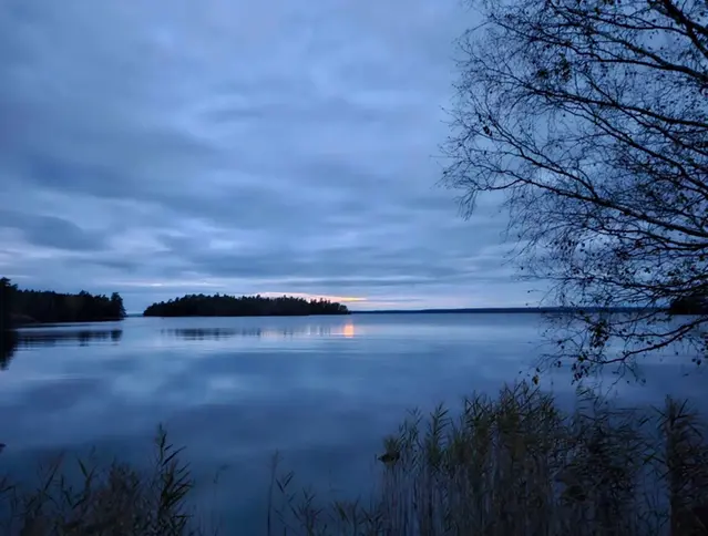Skymningsbild över Vättern, vidsträckt vattenyta med öar och solnedgång i fonden