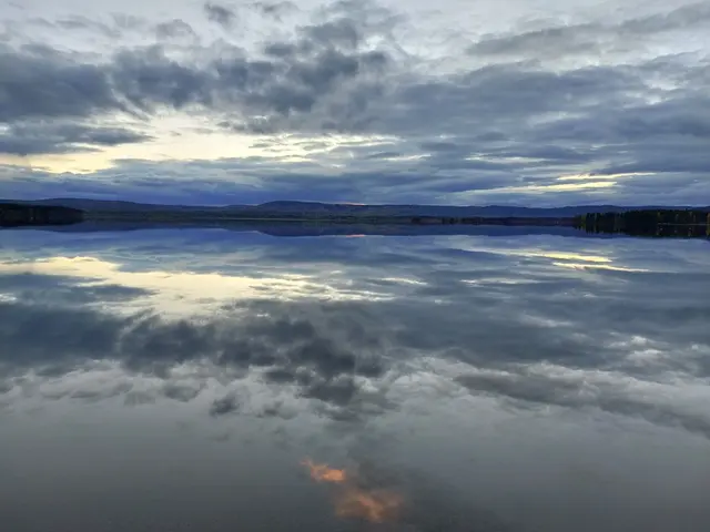 Skymning över sjöyta, fjäll i bakgrunden.