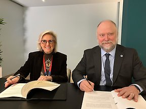 A woman and a man look into the camera after signing an agreement.