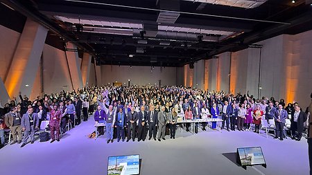 Författare för IPCC:s AR7 står tillsammans i ett stort rum och vissa av dem håller upp sina armar.