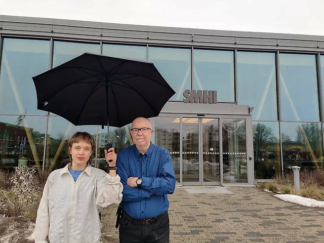 Två forskare står under ett paraply.