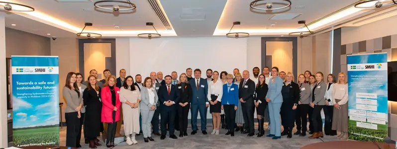 Group photo of about 30 people. Project banners on each side of the group.