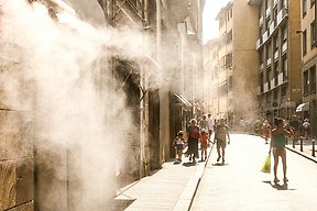 Personer går i stan under den varma solen.