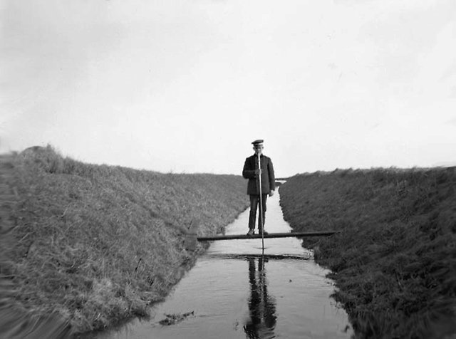 Pojke på planka i dike. Svart vid. 1900-tal