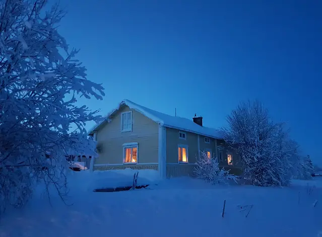 En insnöad stuga i den isblåa polarnatten.