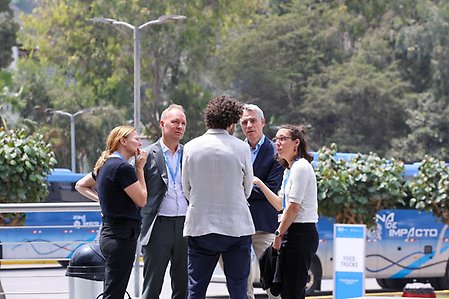 Fem personer står i klunga utomhus och pratar