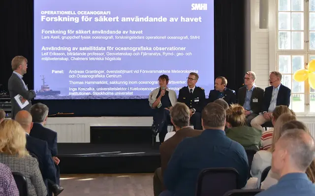 En sittande panel på fem personer och en moderator på scenen.