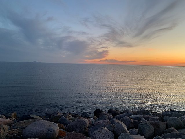 Bild med solnedgång och några molnstrimmor på himlen