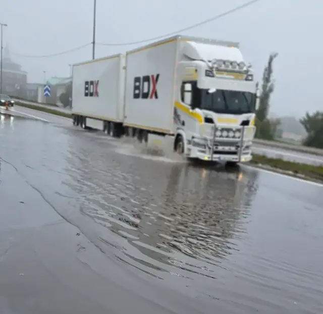 Foto av långtradare som passerar översvämmat område av E4 i Härnösand den 7 september 2025.