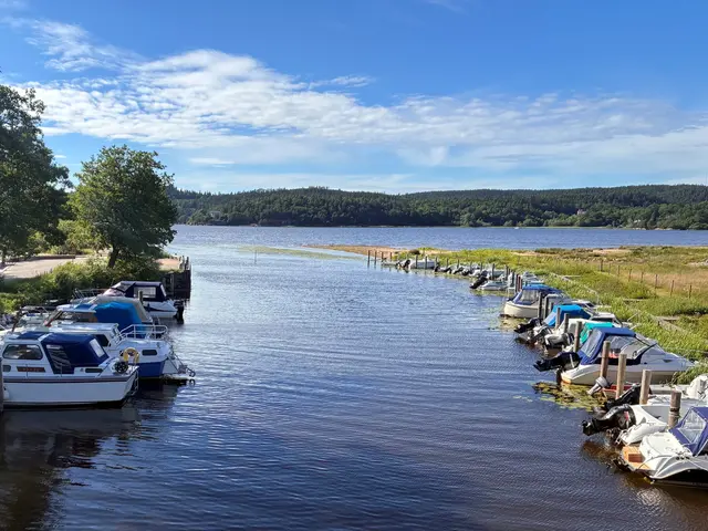 Vattendrag med fritidsbåtar, i bakgrunden en sjö.