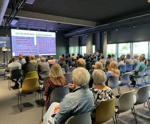 Många personer sitter i en sal och lyssnar på ett seminarium.
