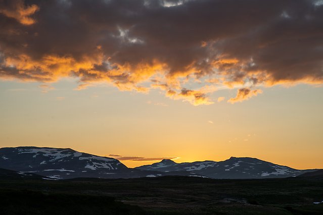 Siluett av en fjälltopp i solnedgång.