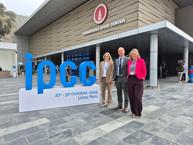 Tre personer står utanför en byggnad