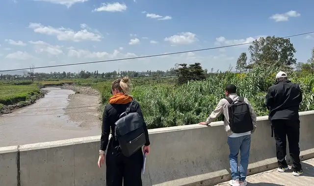 People standing on a bridge looking down on the river.