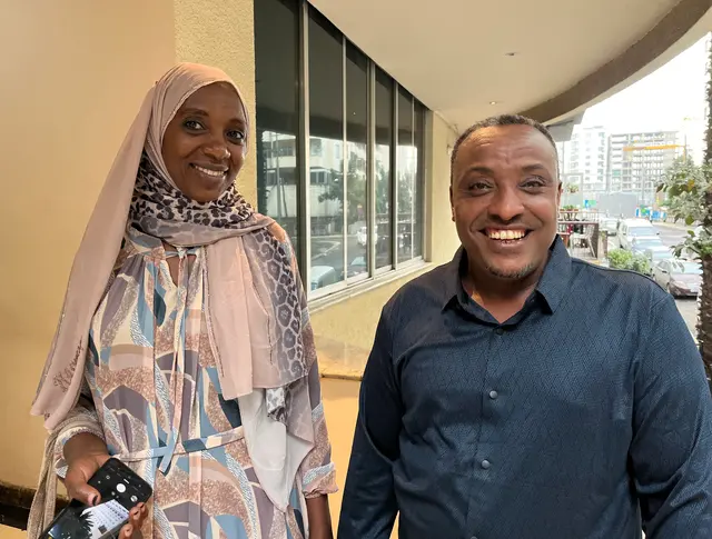 A woman and a man standing outside in a town.