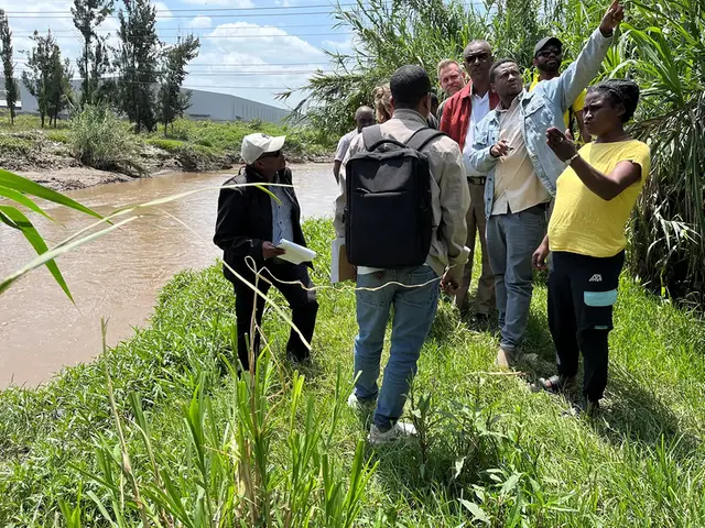 A group of peaople standing at a river discussing.