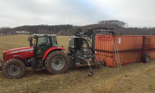 Traktor med pump bakom som pumpar gödsel ur container