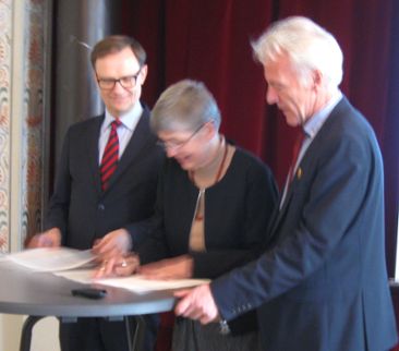 Tre personer skriver på ett avtal