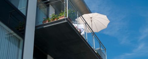 Balkong med glasräcke och parasoll och växer på