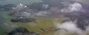 Flygbild över grönskande landskap genom moln, foto 