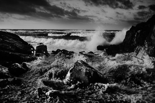 Skummiga havsvågor sköljer in över klippor.