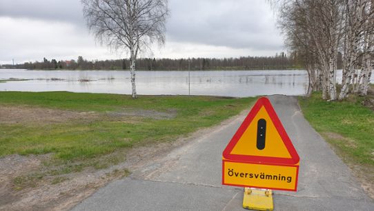 Vattendraget har svämmat över sina gränser och en varningsskylt för  översvämning är uppsatt 