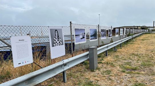 Flera förstorade fotogrfier uppsatta på ett staket i en hamn.