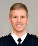 Porträtt på en leende man i uniform.