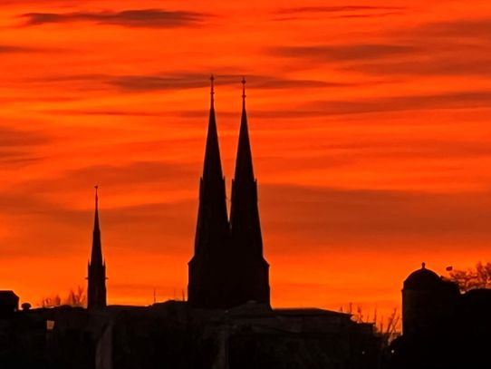 Rödglödgad himmel i Uppsala med silhuetten av domkyrkan och slottet.