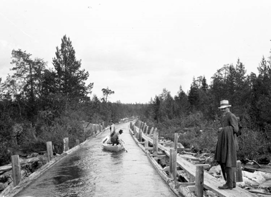 Män paddlar i kanal av trä