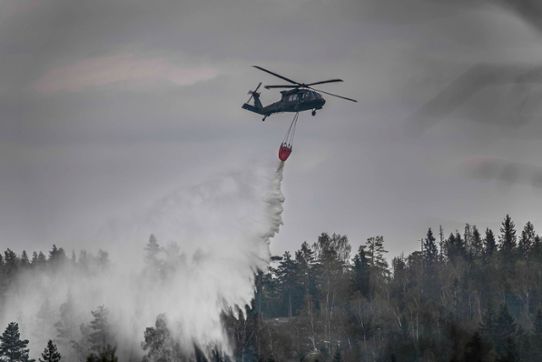 helikopter som sprider vatten över skog