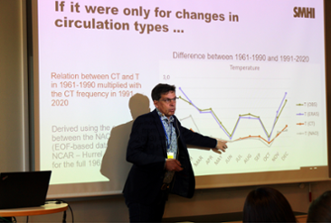 Erik Kjellström står framför en projektion av en presentation och visar en graf. 