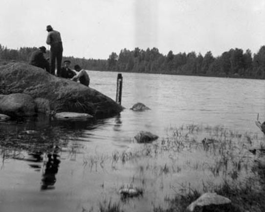Svartvit bild på  män vid sjö