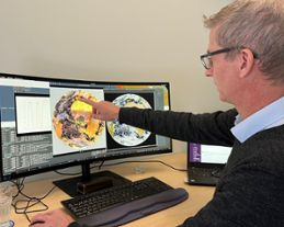 En man visar satellitbilder på sin datorskärm.