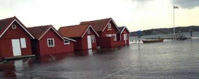 Röda hus vid havet. Parkeringen framför huset är översvämmad av havsvatten.