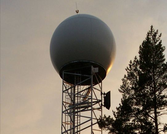 Radaranläggning med radom högt upp på en mast, foto.