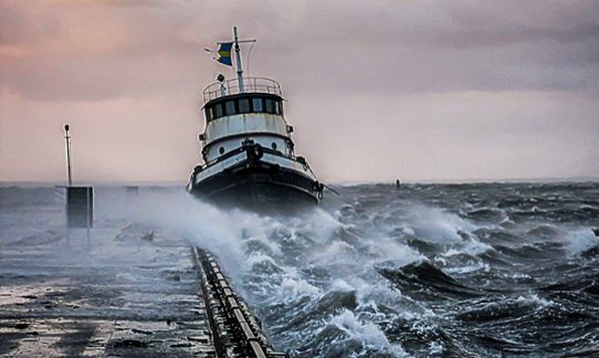 Stormvindar och vågor piskar ett fartyg vid kaj, foto.