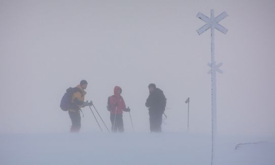 Fjällväder- skidåkare vid led i snöstorm.